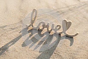 Wooden word love on sandy beach background. Concept of romantic holiday anniversary, proposal, valentines day greeting