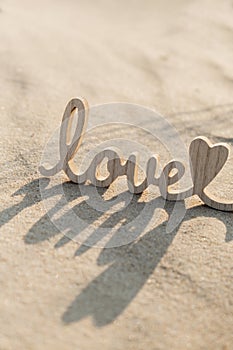 Wooden word love on sandy beach background. Concept of romantic holiday anniversary, proposal, valentines day greeting