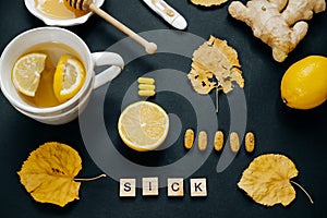 Wooden word sick, honey, Tea with lemon, thermometer, ginger, ta