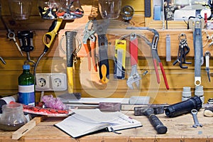 Wooden workbench at workshop. Lot of different tools for diy and repair works. Wood messy table with notebook. Copyspace. Labour d