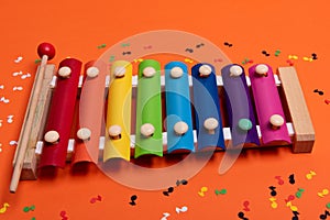 Wooden xylophone in rainbow colors for children an isolated on orange. Paper colorful musical notes surrounding