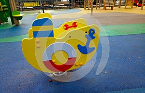 A wooden yellow boat on the playground with a rubberized coating. Children's sports hobbies