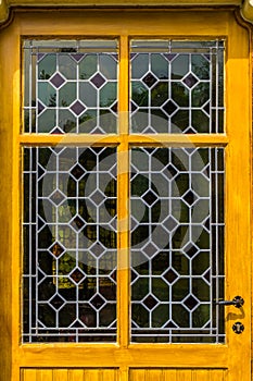 Wooden yellow door with tainted glass pattern in diverse colors, Vintage background