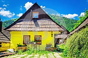Dřevěná žlutá chata v tradiční vesnici na Slovensku