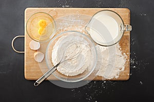 Wooder chopping board ,flour and milk on chalkboard background