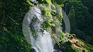 Woodland waterfall falling rocks closeup. Drone shot vivid water cascading mossy