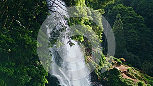 Woodland waterfall falling rocks closeup. Drone shot vivid water cascading mossy