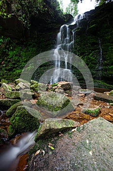 Woodland waterfall scene slow moving river stream in the Derbyshire Peak District National Park. Shot with slow shutter speed.