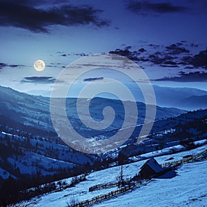 Woodshed on the hillside in winter mountains at night