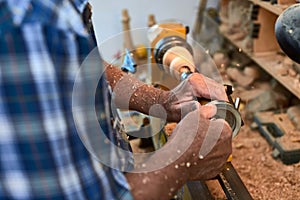 The woodturner work. Man`s arms with cutter in action.