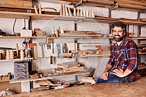 Woodwork craftsman in studio with shelves of wood pieces