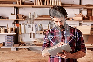 Woodwork designer using a digital tablet in his studio