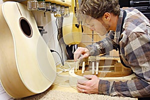 Woodworker Building Guitar in Workshop