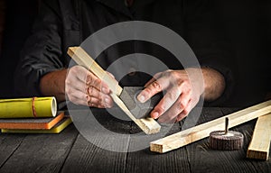 The woodworker cleans a wooden planks with abrasive tools. Hands of the builder close-up during work. Renovation or construction