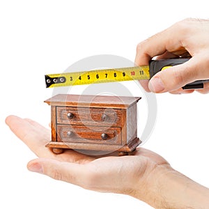 Woodworker measuring chest of drawers with a tape measure