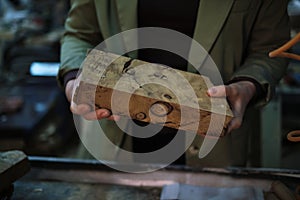 A woodworker’s hands carefully assess a piece of burl, where the swirls and knots speak of the wood’s journey from