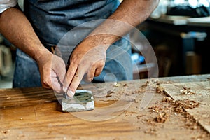 Closeup of Carpenter's Hand Sharpening Chisel