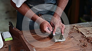 Woodworker is shown sharpening a chisel on a whetstone for making a classical guitar