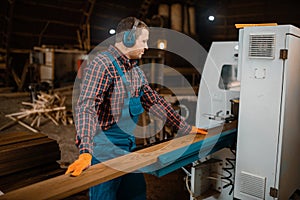 Woodworker works on machine, lumber industry photo