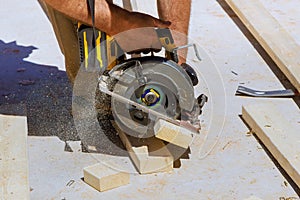 Woodworking carpenter cutting wooden beams with a handsaw photo