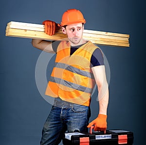 Woodworking concept. Carpenter, woodworker, labourer, builder on calm face carries wooden beams on shoulder. Man in
