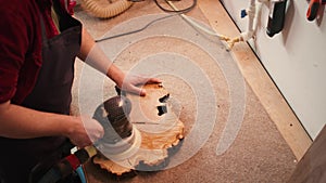 Woodworking specialist uses angle grinder on wood, close up shot