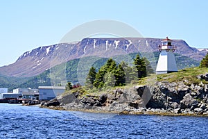 Woody Point Lighthouse along the shore of Bonne Bay with The Tablelands on the horizon