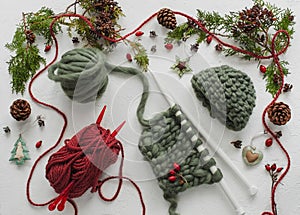 Wool knitting with new year`s decorations. Creen and red colours.