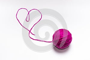 Wool skein pink with a thread in the shape of a heart on a white background