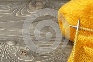 Wool yarn ball and knitting needles on rustic wood