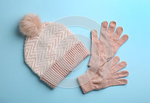 Woolen gloves and hat on light blue background, flat lay