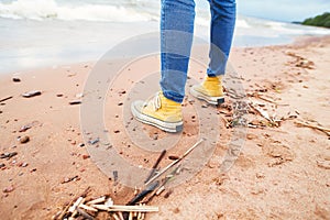 Wooman sneakers on the beach. Sea waves at a sand.