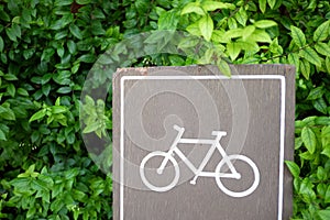 A woonden bicycle signboard with green leaves background