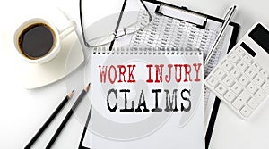 WOR INJURY CLAIMS text on the paper with calculator, notepad, coffee ,pen with graph