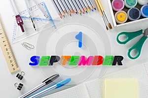 The word `1 September` from plastic letters on a white background with school articles.