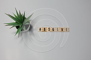 The word Absolve written in wooden letter tiles on a white background