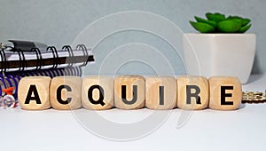 word Acquire on wooden block, business concept