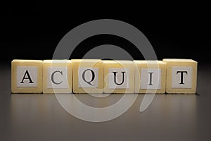 The word ACQUIT written on wooden cubes isolated on a black background