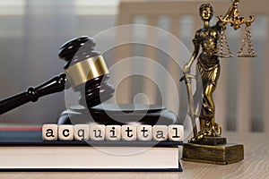 Word  ACQUITTAL composed of wooden dices. Wooden gavel and statue of Themis in the background
