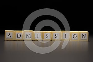 The word ADMISSION written on wooden cubes isolated on a black background photo
