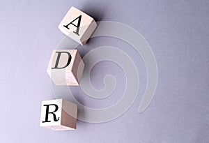 Word ADR on wooden block on the grey background