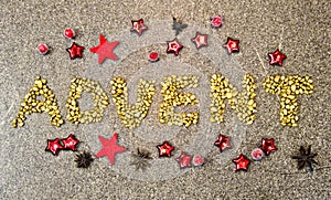 The word â€œadventâ€ flat laying on the ground, from golden pebbels and some festive decoration