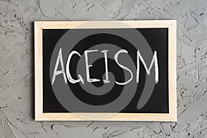 Word `Ageism` written on a small blackboard with wooden frame