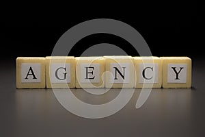 The word AGENCY written on wooden cubes isolated on a black background