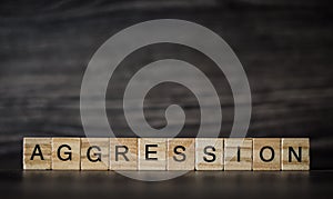 The word aggression, consisting of light wooden square panels on