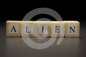 The word ALIEN written on wooden cubes isolated on a black background