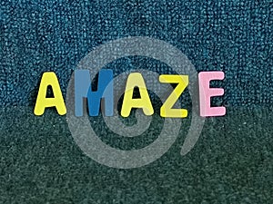 Word amaze made of colourful wooden alphabet against blue background.