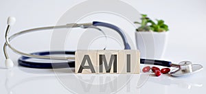 The word AMI is written on wooden cubes near a stethoscope on a white background. Medical concept