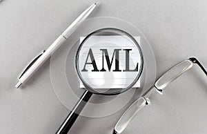 Word AML on sticky through magnifier on grey background