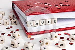 Word Amour written in wooden blocks in a notebook on white woo